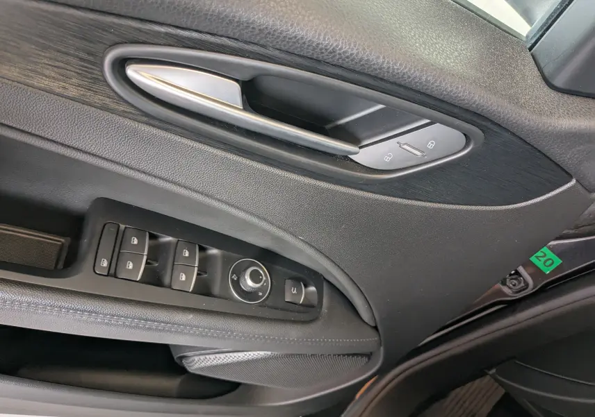 Gros plan sur la porte côté gauche noire de l'Alfa Romeo Stelvio 2023 avec commandes de vitres et poignée argentée.