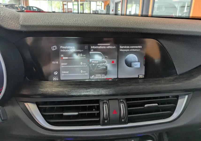 Vue rapprochée de l'écran central multimédia de l'Alfa Romeo Stelvio 2023, affichant les informations techniques et connectées.