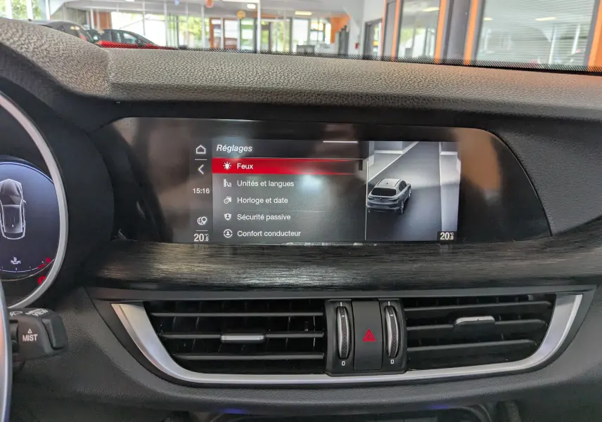 Écran tactile central de l'Alfa Romeo Stelvio 2023 affichant le menu Réglages avec vue du véhicule gris sur la droite.