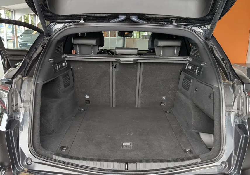Coffre ouvert vu de l'arrière d'un Alfa Romeo Stelvio noir 2023, intérieur spacieux et banquette arrière visible.
