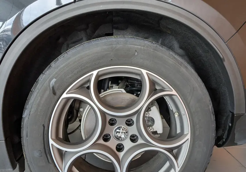 Gros plan sur la roue arrière droite noire d'une Alfa Romeo Stelvio 2023 avec jante aluminium 19 pouces et logo Alfa Romeo.