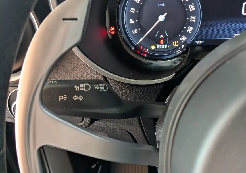 Gros plan sur le compteur digital et la palette de changement au volant d'une Alfa Romeo Stelvio noire, tableau de bord moderne.