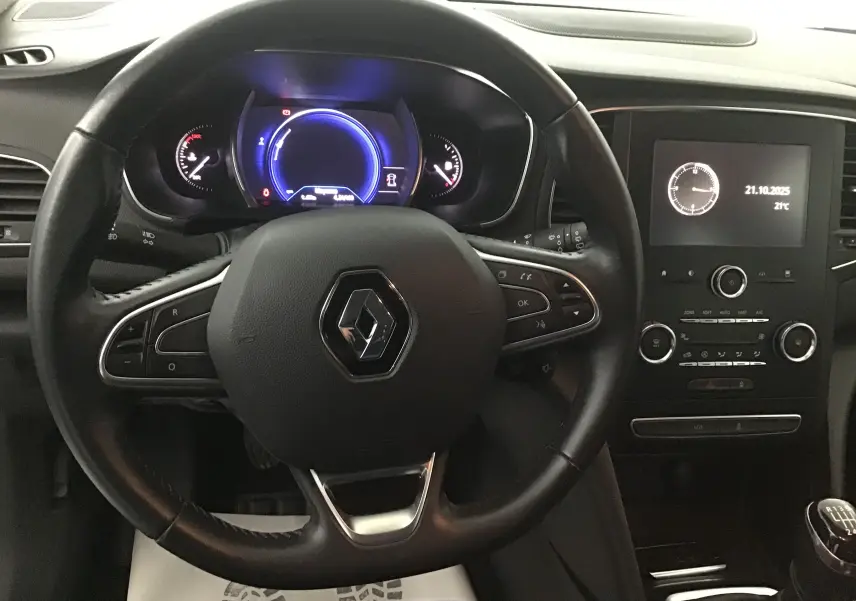 Vue rapprochée du volant Renault avec tableau de bord numérique bleu et console centrale noire de la Mégane IV Berline 2019.