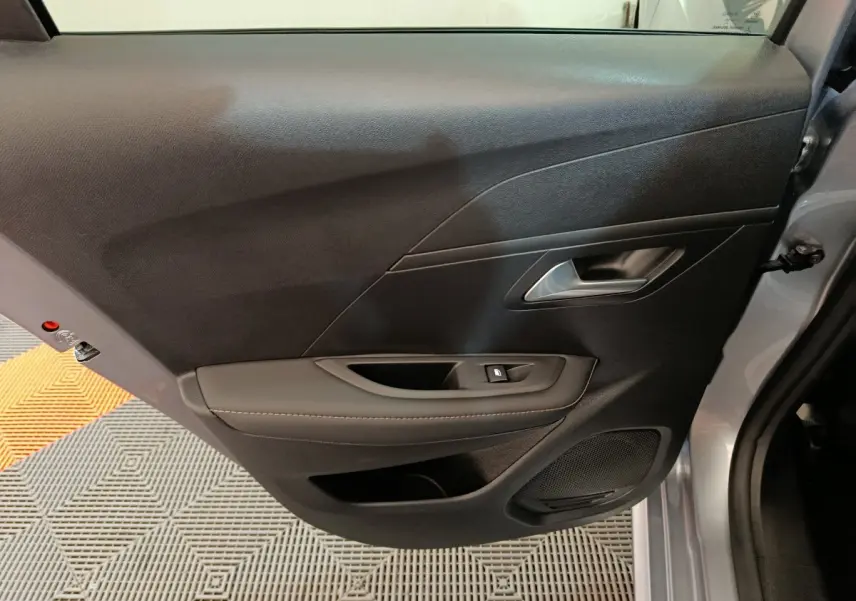 Gros plan sur la porte arrière droite gris clair de la Peugeot 208 PureTech 100 S&S Allure avec poignée et commande de vitre.