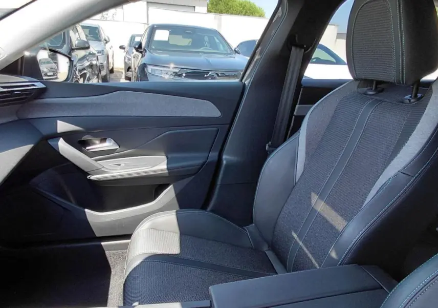 Vue intérieure côté passager avant d'une Peugeot 308 SW gris, mettant en valeur le siège tissu et cuir avec accoudoir central.