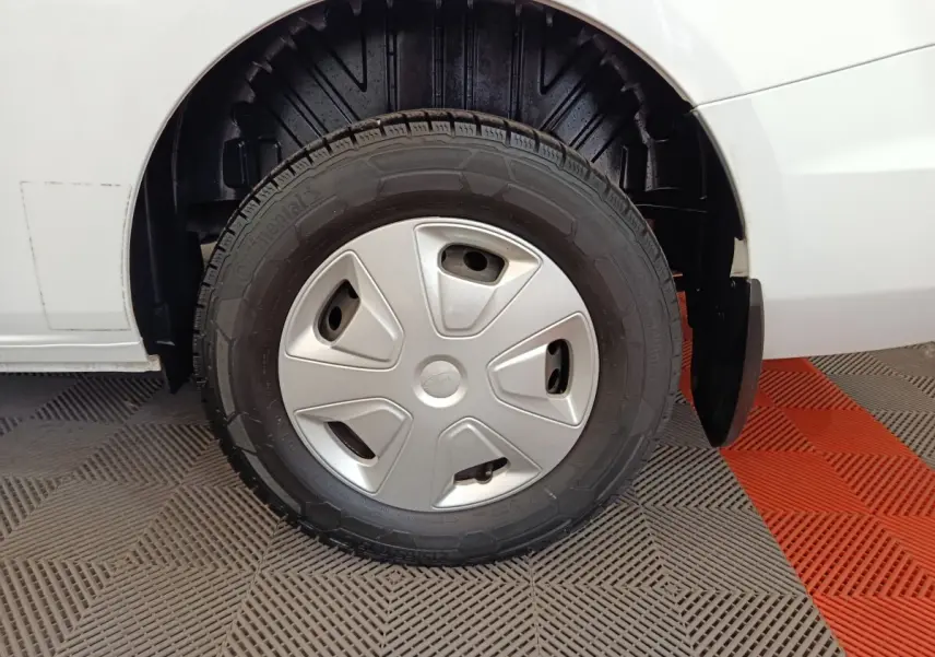 Gros plan sur la roue avant gauche d’un Ford Transit Custom blanc, avec enjoliveur argenté et pneu Continental.