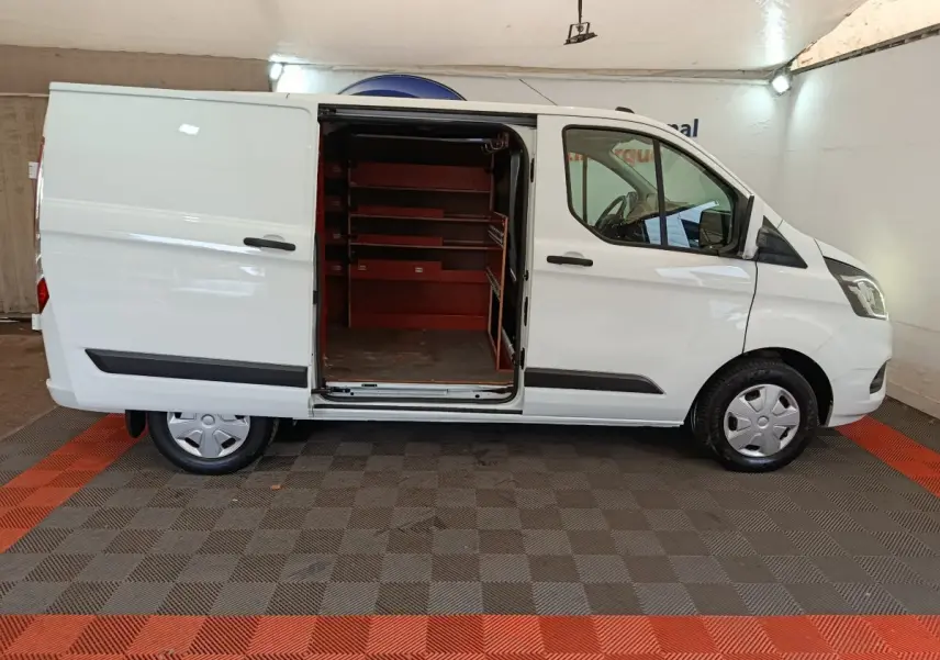 Vue latérale droite d'un Ford Transit Custom blanc 2020 avec porte coulissante ouverte révélant l'intérieur aménagé en étagères rouges.