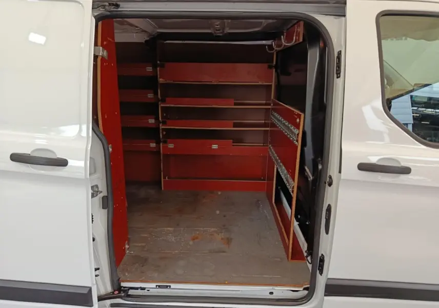 Vue intérieure côté droit du Ford Transit Custom blanc 2020 avec portes latérales ouvertes et aménagements de rangement rouges.