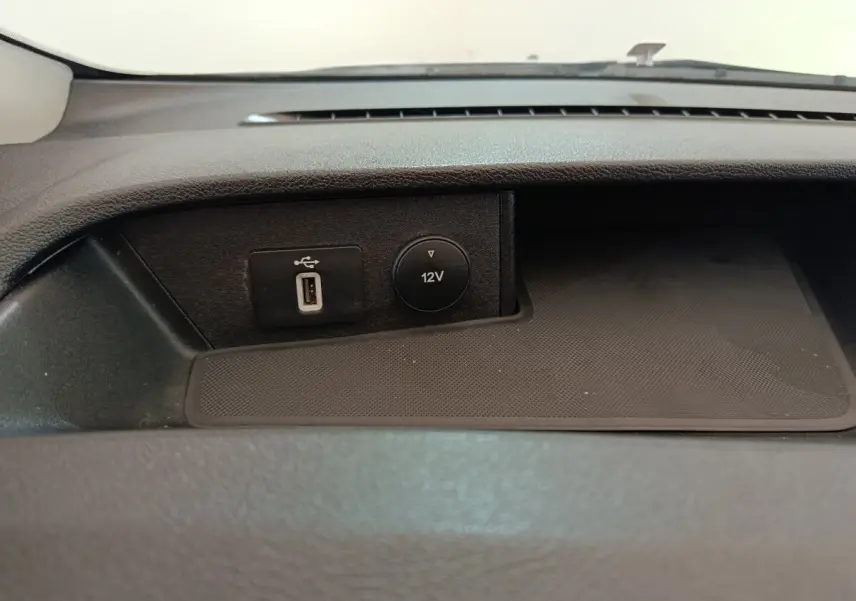 Gros plan sur la prise USB et la prise 12V intégrées dans la console centrale du Ford Transit Custom blanc.