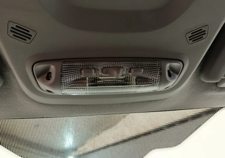 Plafonnier intérieur gris avec trois boutons, visible depuis l’habitacle du Ford Transit Custom blanc.