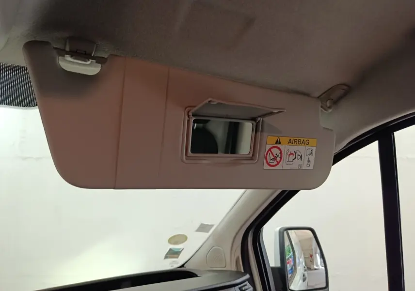 Vue intérieure côté conducteur du pare-soleil beige avec miroir et étiquette airbag dans un Ford Transit Custom blanc.