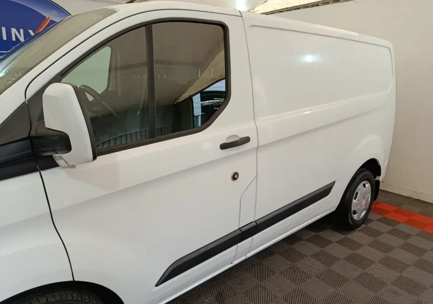 Vue latérale gauche d'un Ford Transit Custom blanc avec porte coulissante et rétroviseur blanc.