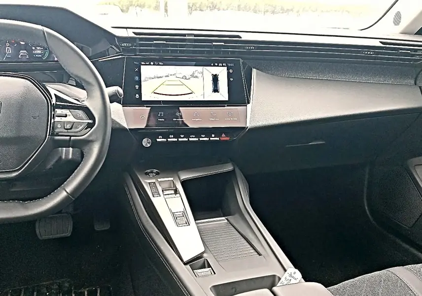 Vue intérieure du tableau de bord et console centrale de la Peugeot 408 Hybrid 145 allure gris sellenium avec écran tactile affichant la caméra de recul.