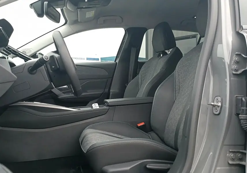 Vue intérieure côté conducteur de la Peugeot 408 Hybrid gris sellenium, montrant les sièges tissu et cuir avec accoudoir central.