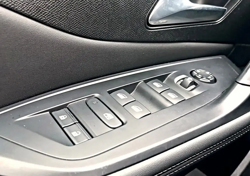 Gros plan sur la commande des vitres et rétroviseurs côté conducteur de la Peugeot 408 Hybrid 145 allure gris sellenium.