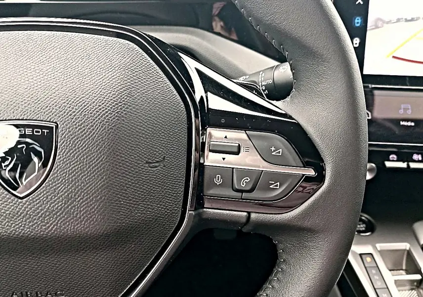 Gros plan sur le volant cuir noir multifonction de la Peugeot 408 Hybrid 145 allure 2024 avec commandes audio et vocales.