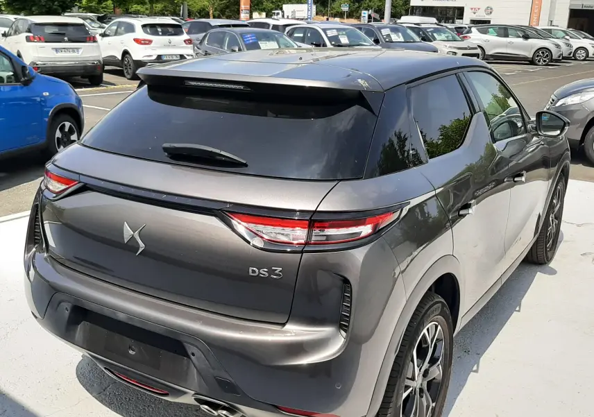 Vue 3/4 arrière droite d'un DS3 Crossback gris platinium métallisé avec toit noir et feux arrière LED distinctifs.