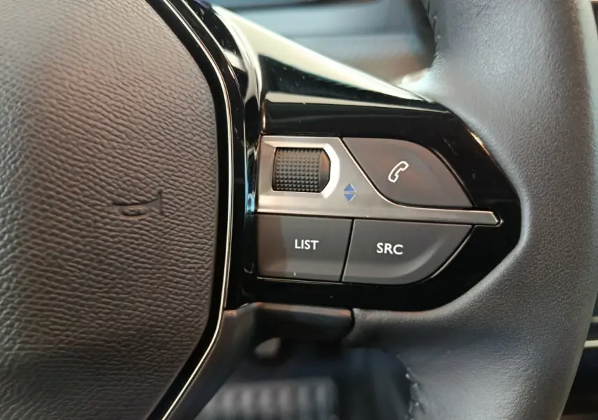 Gros plan sur les commandes du volant cuir à droite de la Peugeot 208 PureTech 100 S&S Allure 2025.