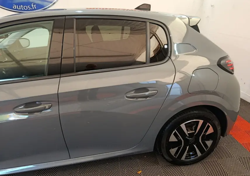 Vue latérale côté droit d'une Peugeot 208 PureTech 100 S&S Allure gris foncé avec jantes noires et détails modernes.