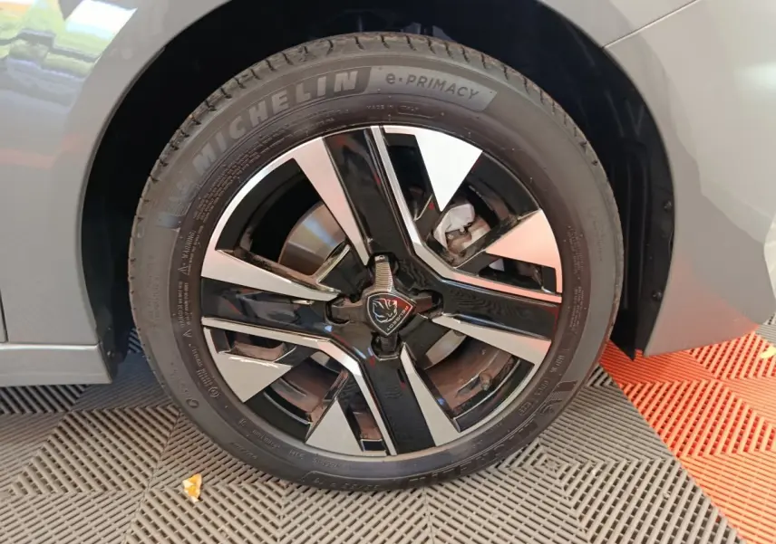 Gros plan sur la roue avant droite gris foncé de la Peugeot 208 PureTech 100 S&S Allure avec jante noire et argentée.