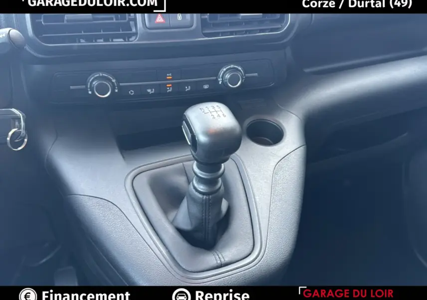 Gros plan sur le levier de vitesse manuel du Peugeot Rifter bleu 2024, avec commandes de climatisation en arrière-plan.