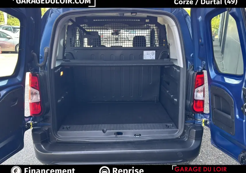 Vue arrière du Peugeot Rifter bleu 2024 avec portes ouvertes montrant le grand espace de chargement vide et la grille de séparation.