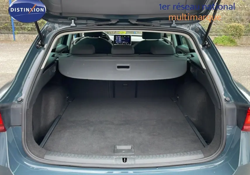 Vue arrière du coffre ouvert d'une SEAT LEON ST 2025 bleu fjord, montrant l'espace de chargement et la plage arrière.