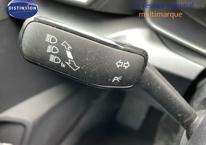 Gros plan sur la manette de clignotant noire à l'intérieur du SEAT LEON ST bleu Fjord, avec pictogrammes blancs visibles.