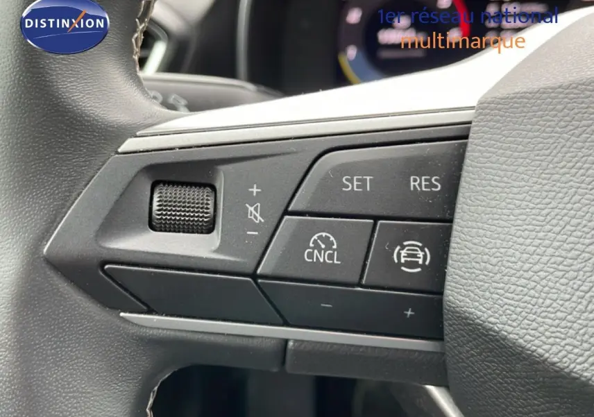 Gros plan sur les commandes de régulateur de vitesse au volant d’un SEAT LEON ST 2.0 TDI 115CH STYLE XL, intérieur gris-noir.