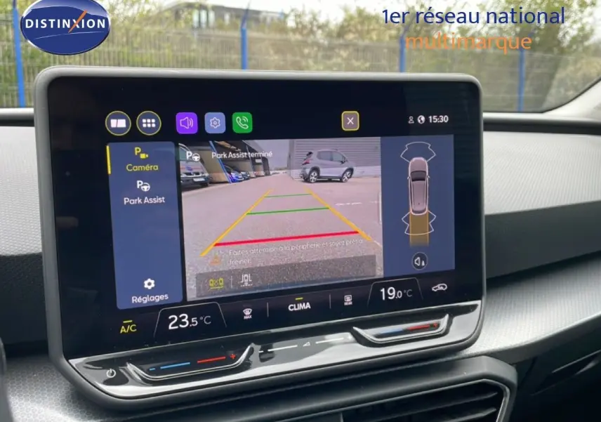 Écran central tactile affichant la caméra de recul et l'assistance au stationnement dans un SEAT Leon ST bleu Fjord.