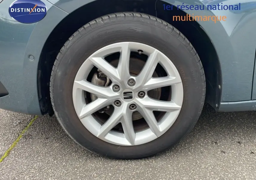 Gros plan sur la roue avant droite d'une SEAT LEON ST bleu fjord, mettant en valeur la jante alliage et le logo central.