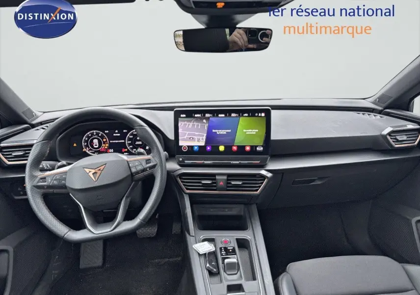 Vue intérieure frontale du tableau de bord et volant noir de la CUPRA LEON ST 2024 avec écran tactile central allumé.