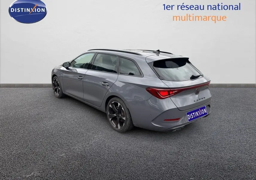 Vue 3/4 arrière droite d'une CUPRA LEON ST gris Graphene avec jantes noires et feux arrière LED allumés.