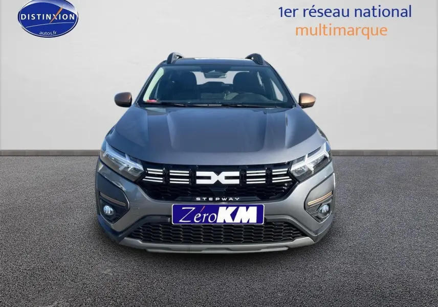 Vue frontale d'une Dacia Sandero Stepway gris schiste avec calandre noire et barres de toit visibles.