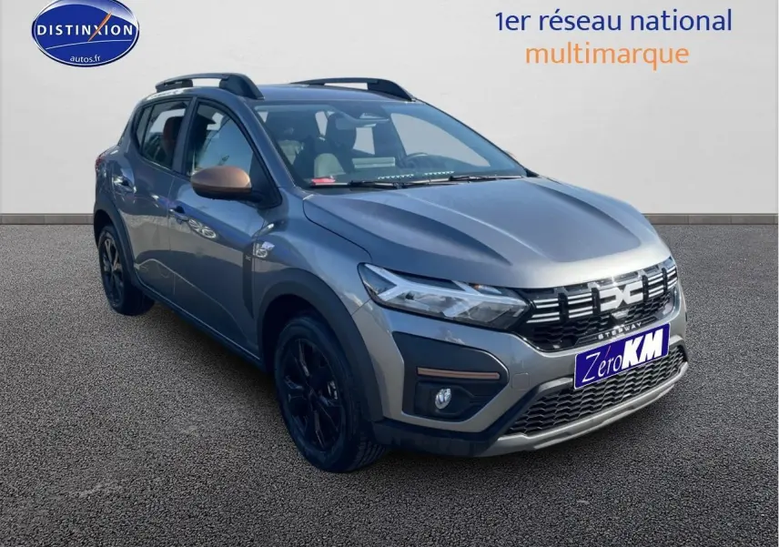 Dacia Sandero Stepway gris schiste vue 3/4 avant droit avec barres de toit et jantes noires.