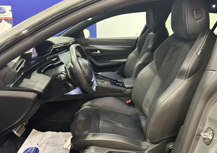 Vue intérieure côté conducteur du Peugeot 508 SW 2024 gris Selenium, sièges cuir noirs avec surpiqûres contrastées.