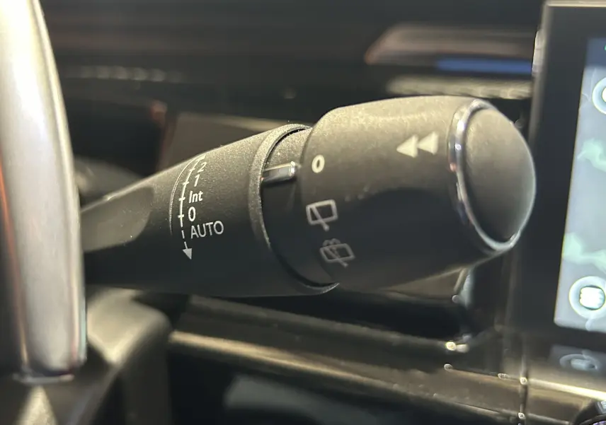 Gros plan sur la commande d'essuie-glace à gauche du volant dans l'habitacle d'une Peugeot 508 SW 2024.