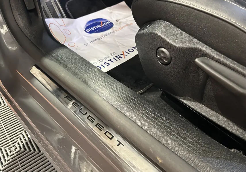Gros plan sur la plaque de seuil de porte Peugeot gris Selenium côté conducteur avec siège en cuir noir et tapis Distinxion.