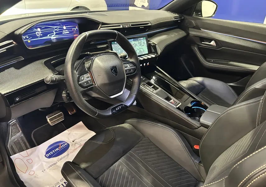 Vue intérieure côté conducteur de la Peugeot 508 SW GT 2024 avec tableau de bord numérique et finitions cuir noires.