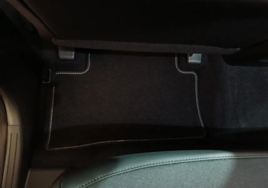 Tapis de sol noir avec surpiqûres blanches côté passager arrière du Hyundai Tucson gris clair 2025 hybride.