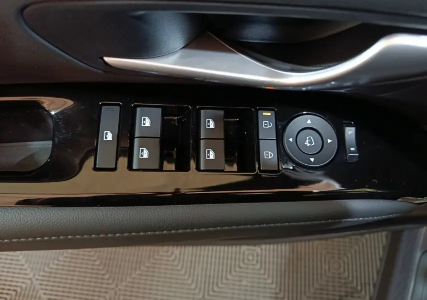 Vue rapprochée des commandes de lève-vitres et rétroviseurs sur la porte intérieure côté conducteur du Hyundai Tucson gris clair 2025.