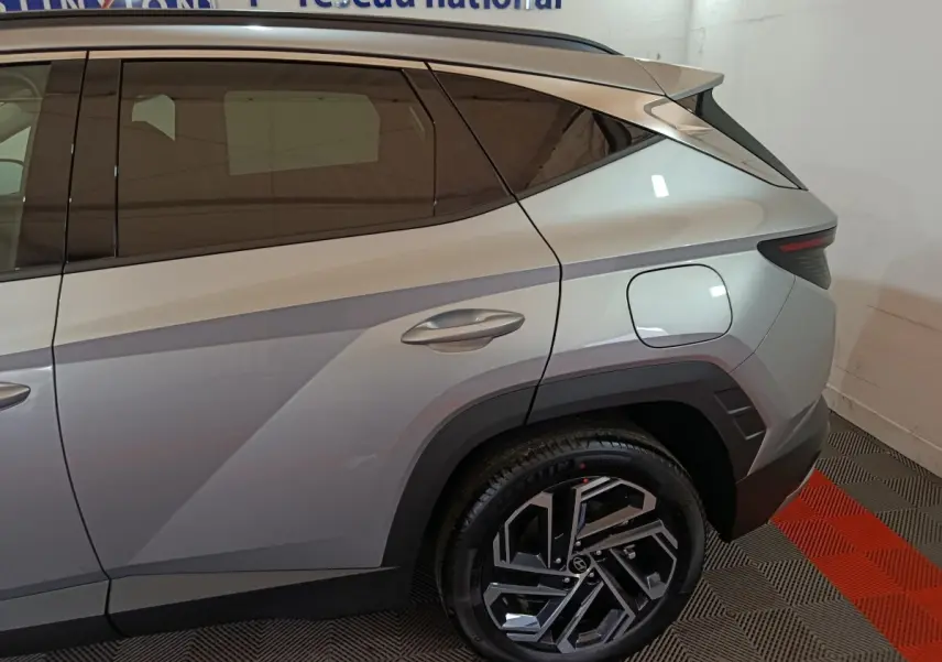 Vue côté droit arrière du Hyundai Tucson 2025 gris clair avec jante alliage noire et détails de carrosserie anguleux.