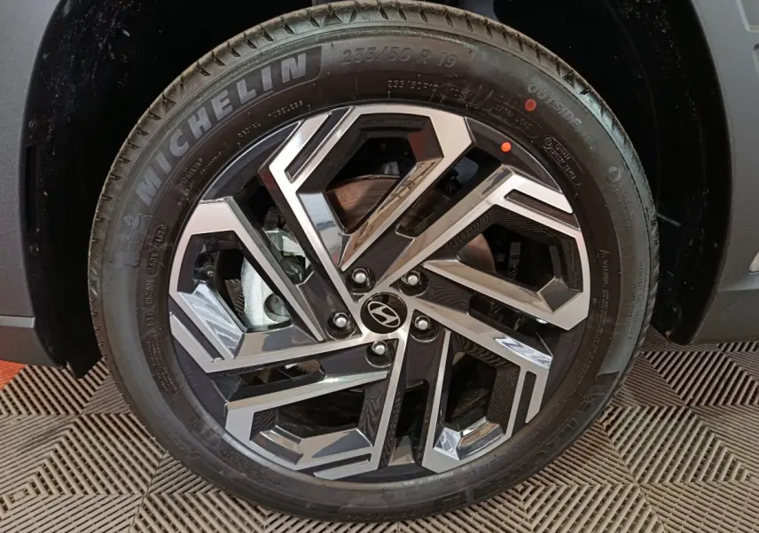 Gros plan sur la jante avant droite du Hyundai Tucson gris clair 2025 avec logo Hyundai et pneu Michelin.