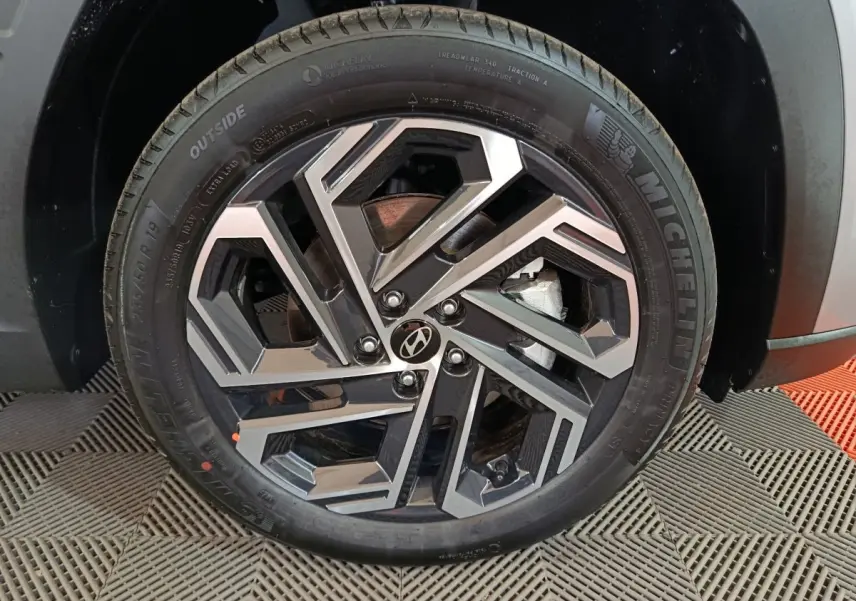 Gros plan sur la roue avant droite du Hyundai Tucson 1.6 Hybrid 239 Creative 2025, jante alliage bicolore et pneu Michelin.