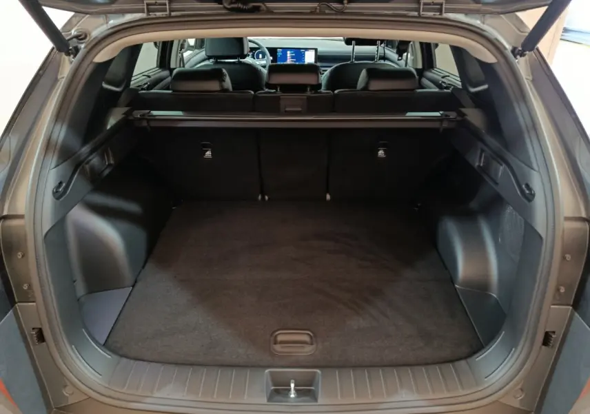 Coffre ouvert d’un Hyundai Tucson gris clair 2025, vue arrière montrant l’espace de chargement et la tablette cache-bagages.