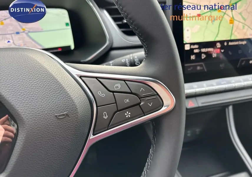 Gros plan sur le volant côté droit du Renault Captur 2025, avec commandes intégrées et écran tactile de navigation en arrière-plan.