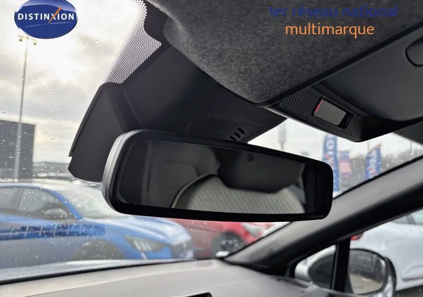 Vue intérieure du rétroviseur central d’un Renault Captur gris rafale métal avec toit noir, sous un ciel nuageux et pluie légère.
