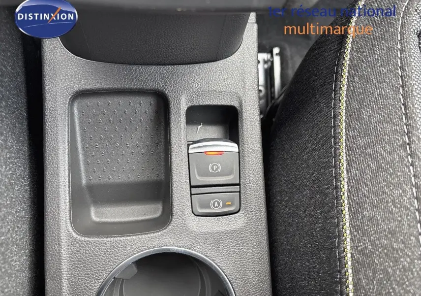 Gros plan sur la console centrale avec les boutons de frein à main électrique et auto hold, tissu noir avec surpiqûres jaunes.