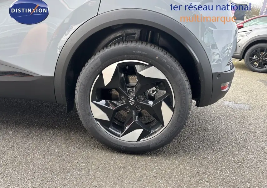 Gros plan sur la roue arrière droite du Renault Captur gris Rafale métal, soulignant la jante noire et argentée au design géométrique.