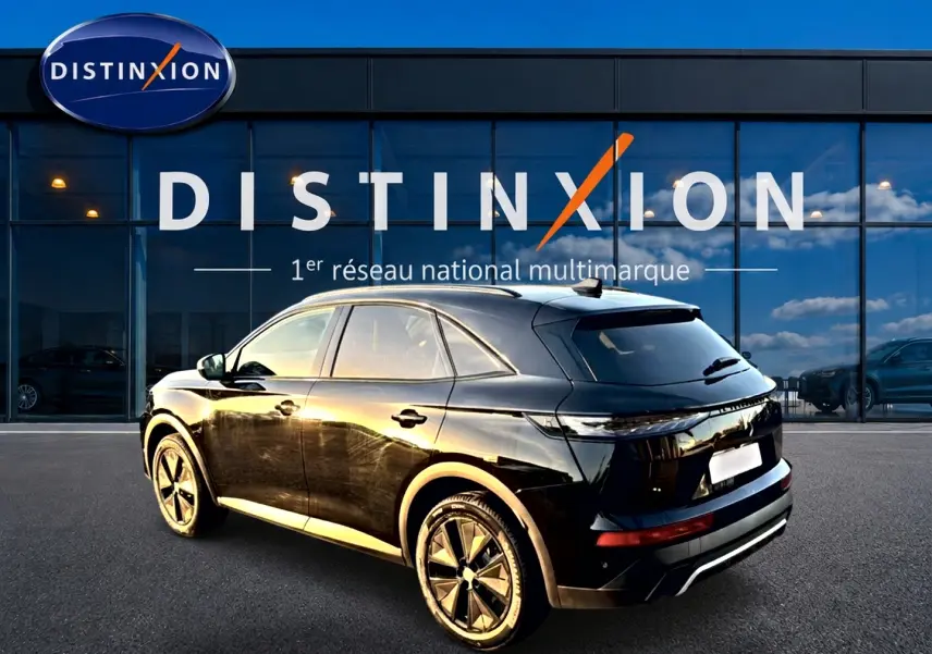 DS7 noir vue 3/4 arrière droit, avec jantes alliage et vitres arrière surteintées, stationné devant un showroom Distinxion.